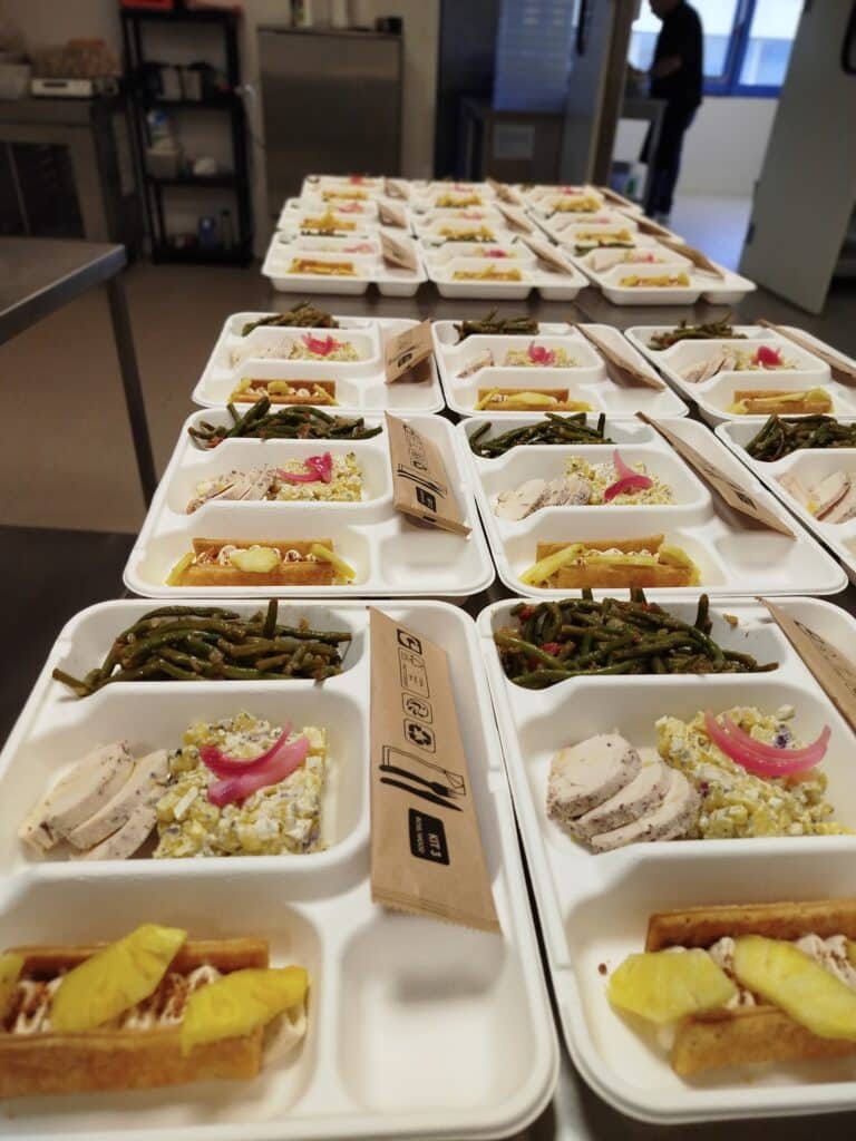 Plateaux Repas Traiteur Préparés : Poulet, Salade et Végétaux Plusieurs plateaux repas jetables blancs remplis de tranches de poulet, salade de pommes de terre, haricots verts et dessert, avec couverts en bois 'KIT 3 BOWL/WOOD'.