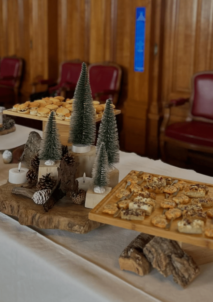 Buffet de cocktail dînatoire avec décor rustique de Noël Buffet festif de canapés et hors-d'œuvre avec sapins miniatures et décoration boisée rustique.