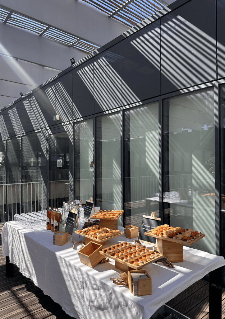 Buffet Traiteur de Canapés pour Cocktail et Événementiel Buffet traiteur de canapés et boissons sur une table nappée lors d'un événement sur une terrasse ensoleillée.